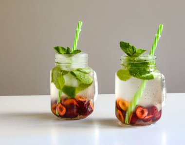 Küçük şişelerde soğuk içecekler. Kiraz ve naneli limonata. Mojito kuyruklu. Yaz buzlu içecek. Yazın, böğürtlenli naneli kokteyl. Mason kavanozu ve soğuk içecek. Yüksek kalite fotoğraf