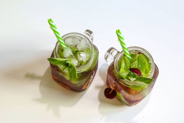 Küçük şişelerde soğuk içecekler. Kiraz ve naneli limonata. Üst Manzara. Mojito kuyruklu. Yaz buzlu içecek. Yazın, böğürtlenli naneli kokteyl. Mason kavanozu ve soğuk içecek..