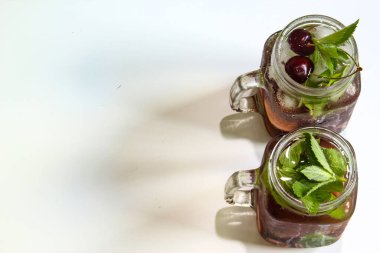 Küçük şişelerde soğuk içecekler. Kiraz ve naneli limonata. Üst Manzara. Mojito kuyruklu. Yaz buzlu içecek. Yazın, böğürtlenli naneli kokteyl. Mason kavanozu ve soğuk içecek..