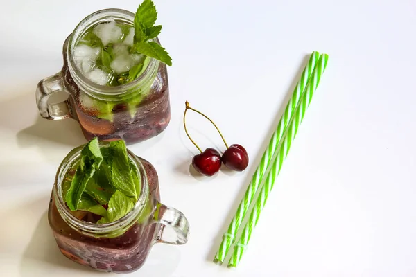 Cold drinks in small bottles. Cherries and mint lemonade. Top view. Mojito coctail. Summer iced refreshment drink. Summer cold mint coctails with berries. Mason jar glass with cold drink.