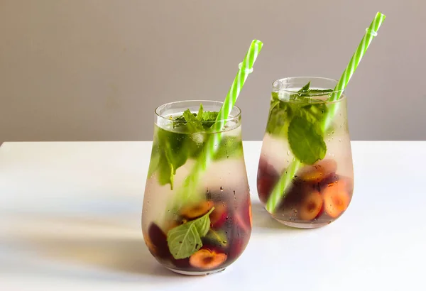 Cold drinks in small glass. Cherries and mint lemonade. Mojito coctail. Summer iced refreshment drink. Summer cold mint coctails with berries. Mason jar glass with cold drink. High quality photo