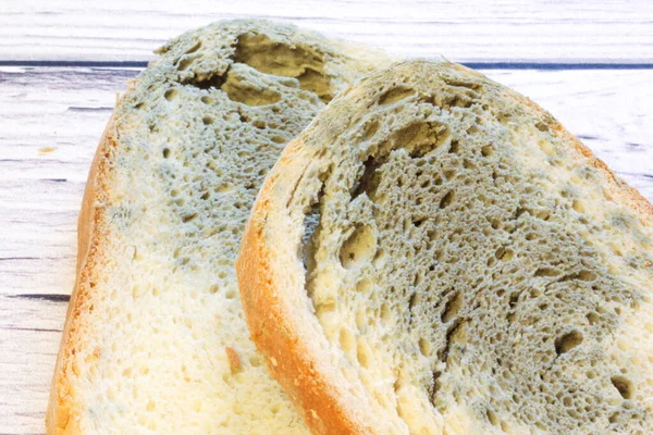 Schimmel wächst schnell auf schimmeligem Brot auf Holzboden. Mehltau auf einer Scheibe Brot. Altes Brot, mit Mehltau bedeckt. — Stockfoto