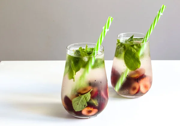 Cold drinks in small bottles. Cherries and mint lemonade. Mojito coctail. Summer iced refreshment drink. Summer cold mint coctails with berries. Mason jar glass with cold drink. High quality photo