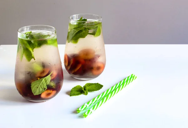 Cold drinks in small bottles. Cherries and mint lemonade. Mojito coctail. Summer iced refreshment drink. Summer cold mint coctails with berries. Mason jar glass with cold drink. High quality photo