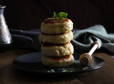 Siyah tabakta ballı tatlı peynir krepleri. Ev yapımı peynirli kek tarifi. Geleneksel Rus yemekleri. Yüksek kalite fotoğraf