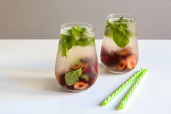 Cold drinks in small glass. Cherries and mint lemonade. Mojito coctail. Summer iced refreshment drink. Summer cold mint coctails with berries. Mason jar glass with cold drink. High quality photo