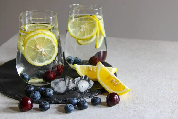 Cold drinks in small bottles. Cherries and lemon lemonade. Mojito coctail. Summer iced refreshment drink. Summer cold mint coctails with berries. Mason jar glass with cold drink. High quality photo