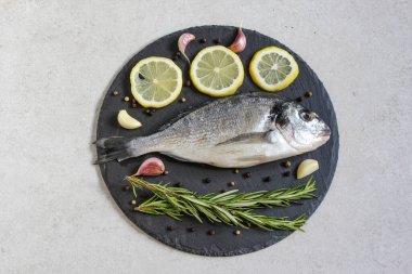 Gri bir zemin üzerinde baharat ve limon bulunan taze, organik deniz dorado 'su. Uzayı kopyala Üst görünüm