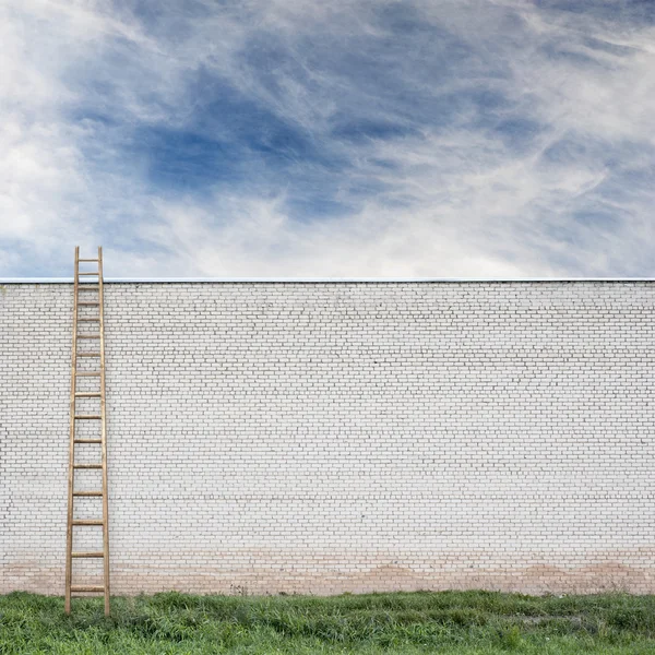 Blauwe lucht achter de grote wand met een houten ladder — Stockfoto