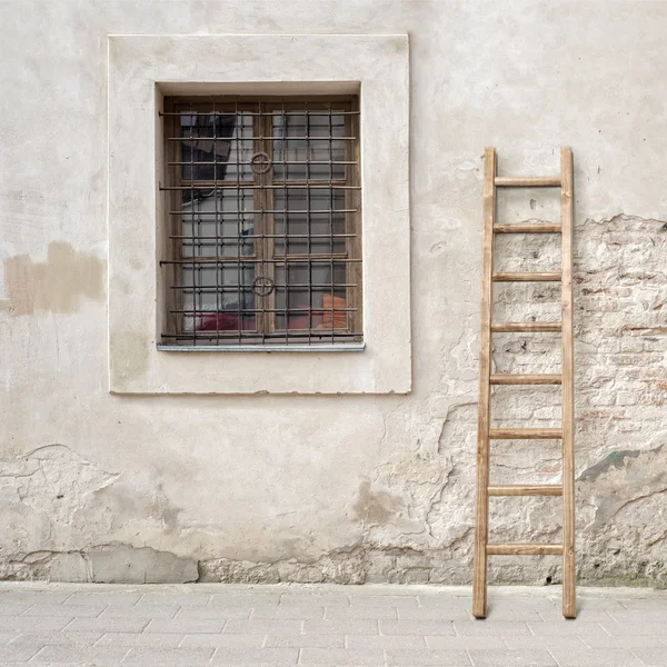 Abandoned cracked brick wall with a window and wooden ladder — Stock Photo, Image