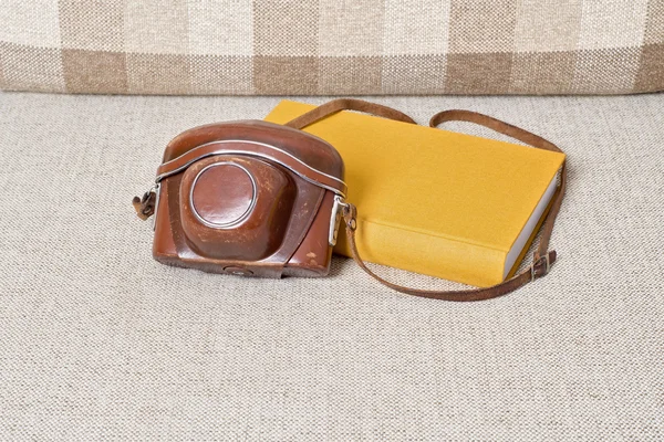 Old vintage camera and yellow book on the sofa — Stock Photo, Image