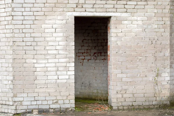 Parede de tijolo rachado branco com uma entrada — Fotografia de Stock