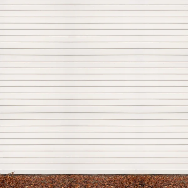 Wooden plank wall, ground covered with fallen leaves — Stock Photo, Image