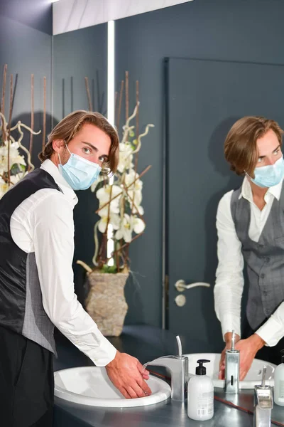 Ung Man Klädd Kirurgmask Och Receptionist Uniform Tittar Kameran Medan — Stockfoto