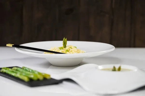 Vyberte zaměření lahodného talíře těstovin a chřestu s rozostřenými pokrmy — Stock fotografie