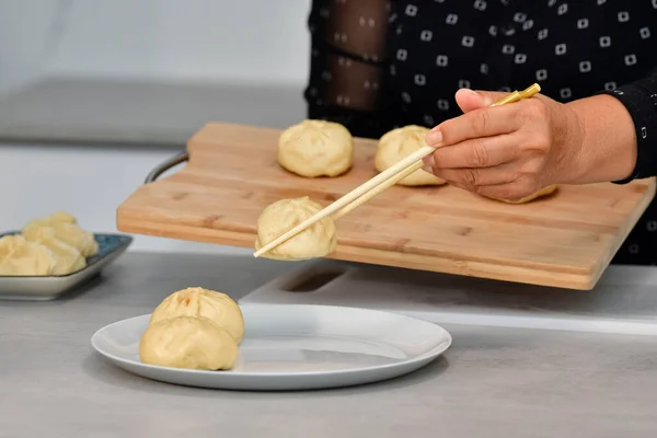 Primo piano di una mano femminile con le bacchette per spostare i tradizionali panini cinesi — Foto Stock