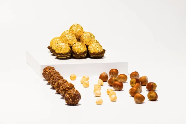 Pohled na zlaté čokoládové bonbóny s lískovými oříšky. Čokoládové cukrovinky a luxusní koncept. — Stock fotografie