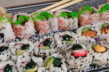 Seçici bir odak noktası ve lezzetli bir uramaki çeşidine odaklanmış zencefil ve çubuk turşusu olmadan yaklaşmak. Suşi ve sağlıklı gıda konsepti.