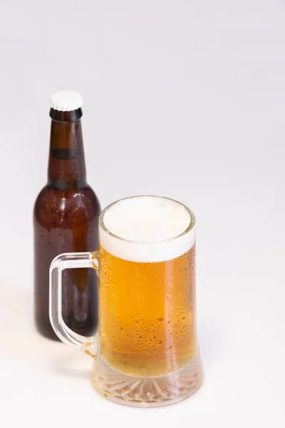 Välj fokus för en frestande kall mugg öl med en ur fokus öl flaska på baksidan — Stockfoto