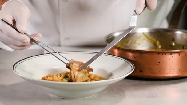 ペンチを使って料理人を閉じ 鍋からひよこ豆のシチューのあるプレートに肉を移動させます 伝統的な料理のコンセプト — ストック動画