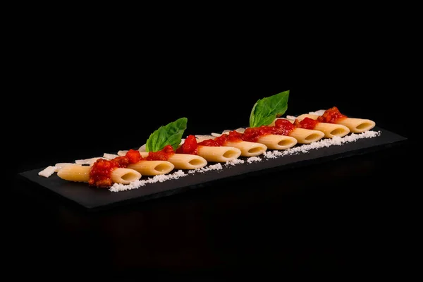 Select focus of an artistic arrangement of macaroni with cheese and tomato on a slate tray — 图库照片