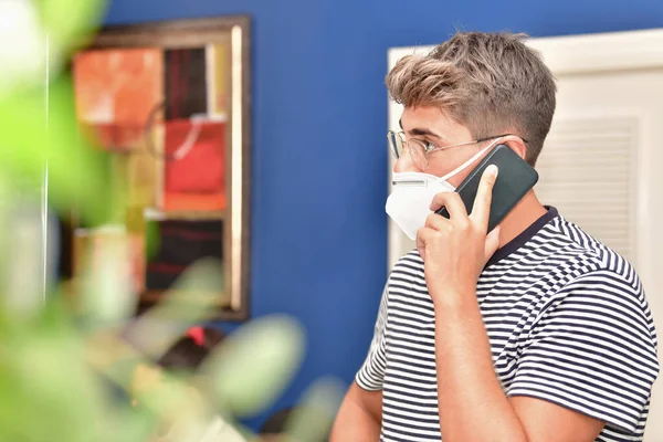 Primer plano de un joven usando una mascarilla y hablando por teléfono — Foto de Stock