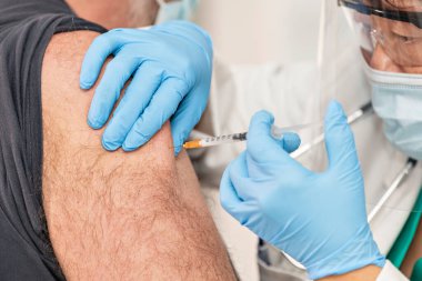 Eldiven takan bir doktor tarafından erkek koluna uygulanan bir aşı. Seçici odaklan ve kapat. Aşı ve sağlık hizmeti kavramı.