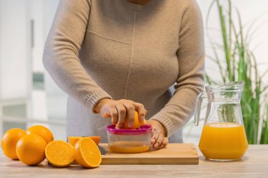 Kadın mutfakta portakal suyu yapıyor.