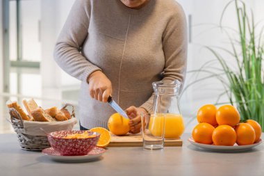 Mutfakta bir kadın portakal kesiyor.