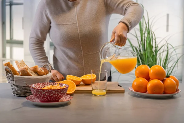 Bardağa taze portakal suyu döken bir kadın.