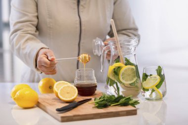 Limonlu bir bal kaşığını tutan el.