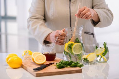 Bir kavanoz limon ve nane yapraklarını kaşıkla karıştırmak