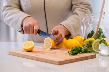 Kesme tahtasındaki limonları nane yapraklarıyla kesiyor.