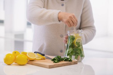 Kavanozda limon ve nane karıştırmak için tahta kaşık kullanmak.