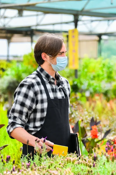 Vista de un joven trabajador con una cirugía en un centro de jardinería — Foto de Stock