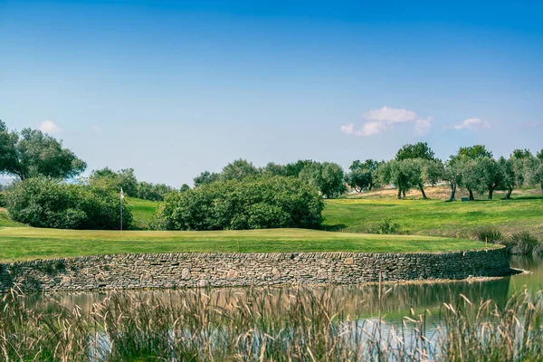 Поле для гольфу зелене з водною небезпекою і кам'яною стіною — стокове фото