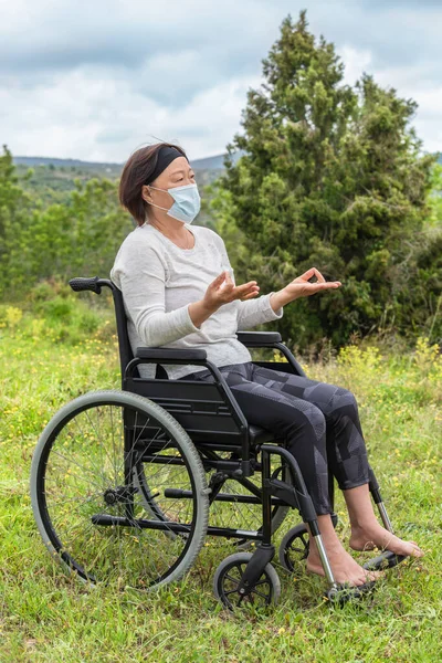 車椅子で瞑想を練習しているアジアの女性は、 covid-19に感染した後の回復を行う — ストック写真