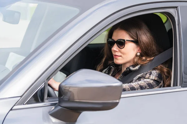 Empresária usando óculos escuros dirigindo um carro — Fotografia de Stock