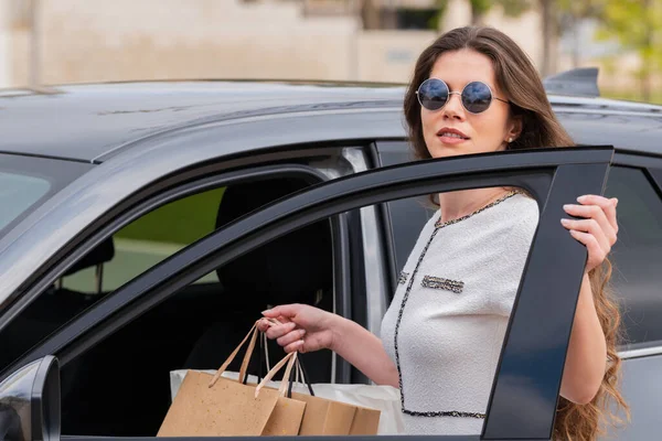 Empresária carregando sacos de compras abrindo uma porta de carros — Fotografia de Stock