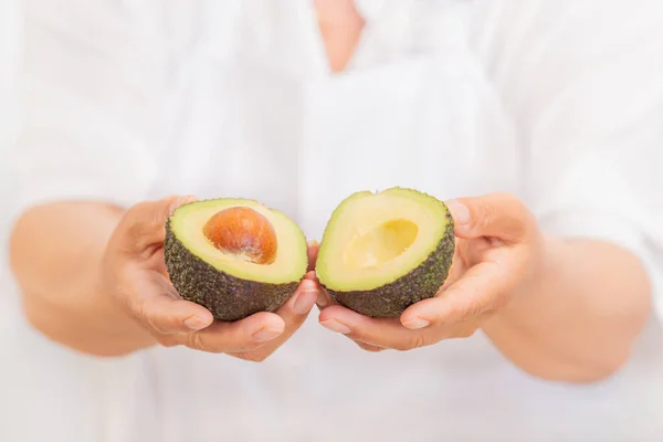 Руки, держащие свежий авокадо разрезанный пополам: Выборочный фокус и закрыть. Концепция здорового питания. — стоковое фото