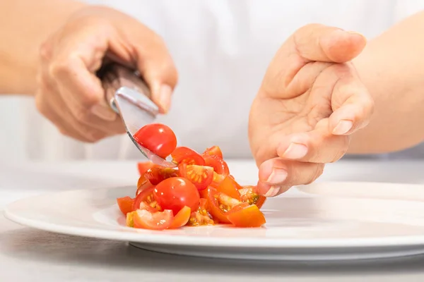 Mani che cadono pomodori appena tagliati su un piatto — Foto Stock