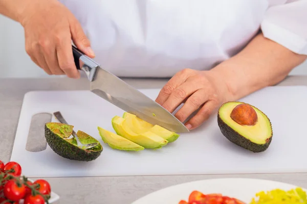 Händer som skär en avokado i tjocka skivor — Stockfoto