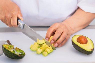 Kesme tahtasındaki taze avokadoyu ustalıkla doğramak.