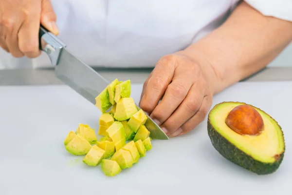 Avokado nyskuren i tärningar med en kökskniv — Stockfoto