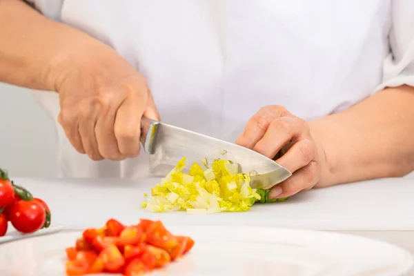 Mani che tagliano lattuga fresca con un coltello su un tagliere — Foto Stock