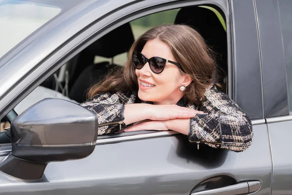 Mulher de negócios sorridente em seu carro olhando para a frente pela janela — Fotografia de Stock