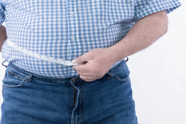 Толстяк проверяет свой жир с помощью измерительной ленты: селективный фокус. Концепция избыточного веса и ожирения — стоковое фото