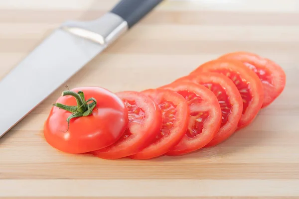 Un pomodoro fresco tagliato isolato su un tagliere di legno: focus selettivo. Concetto di cibo sano — Foto Stock