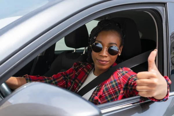Uśmiechnięta afro-amerykanka wykonująca gest w samochodzie: selektywne skupienie. Koncepcja jazdy. — Zdjęcie stockowe
