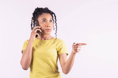 Afro-Amerikalı kadın telefonuyla konuşuyor ve ileri doğru işaret ediyor.